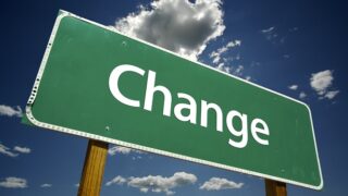 لافتة خضراء كتب عليها "Change" بأحرف بيضاء أمام خلفية سماء وسحب.