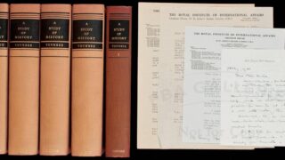 خمسة مجلدات بعنوان "دراسة في التاريخ" لتوينبي، بجانبها وثائق من معهد الشؤون الدولية.