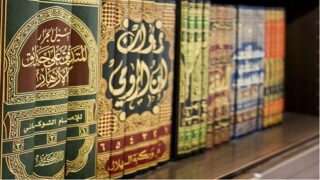 كتب إسلامية مزخرفة بالعربية بألوان مختلفة على رف خشبي.