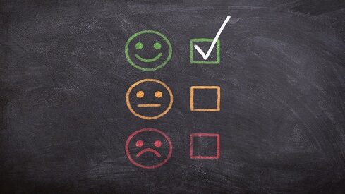 Different facial expressions on a chalkboard with a green check next to the happy face.