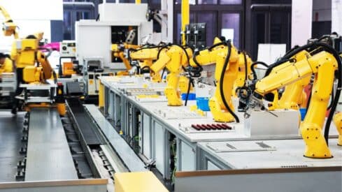 Manufacturing facility with yellow robotic arms on a production line for automated assembly.