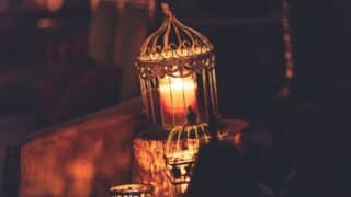 A luminous candle inside a decorative lantern in a warm and dim atmosphere.