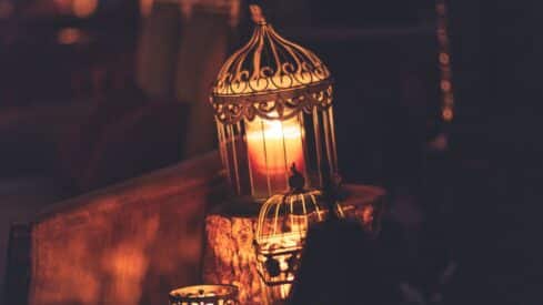 A luminous candle inside a decorative lantern in a warm and dim atmosphere.