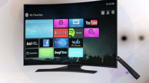 Curved TV screen showing app icons like Netflix, YouTube; remote control beside the TV.