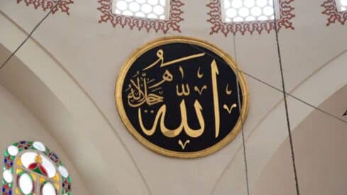 Circular plaque with word of mohammed calligraphy in gold on black, ornate interior with stained glass.