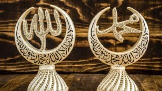 Decorative crescent sculptures with Allah and Mohamed in Arabic calligraphy and stones on a wooden background.