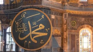 Large circular plaque with Ornate mohammed word in Arabic Arabic calligraphy, ornate interior, and stained glass window.