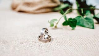 Two metal rings decorated on rough fabric with a green plant in the background.