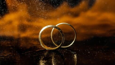 Two interlocking gold rings with warm backlight and delicate gloss.