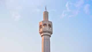 Tall minaret with intricate design against a clear blue sky.