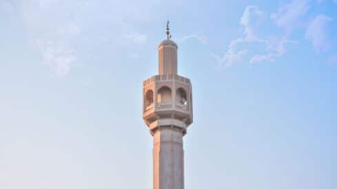 Tall minaret with intricate design against a clear blue sky.