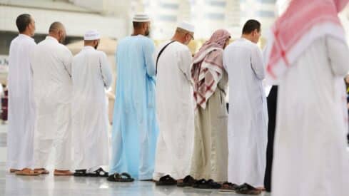 Men in traditional Middle Eastern attire standing in a row outdoors.