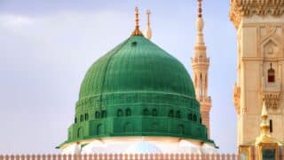 prophet mosque Large green dome with ornate detailing, minaret in background, clear sky.