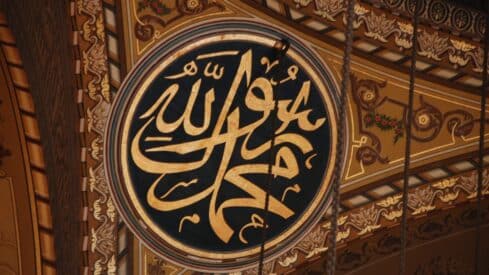 Mohamed in Ornate Arabic calligraphy in gold, dark colors, circular frame, intricate floral design.