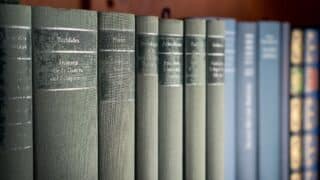 Row of green and blue hardcover books with titles on spines, arranged on a shelf.