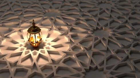 Ornate lantern with warm glow on geometric patterned surface, light and shadow contrast.