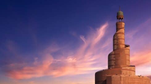 Spiral minaret with helical design against pink and purple clouds at sunset or sunrise.