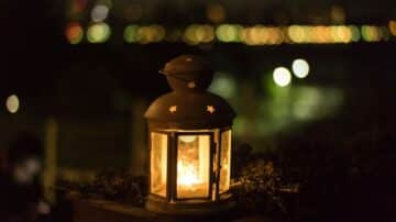 Lit star-patterned lantern outdoors at night, blurred circular lights in the background.