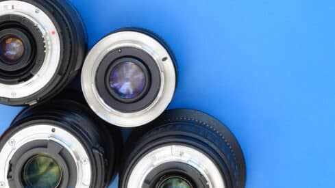 Camera lenses arranged on blue surface with rear elements visible.