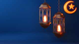 Two glowing lanterns and a crescent moon with star, suspended against a blue background.