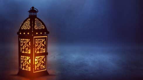 Decorative lantern with intricate patterns glows warmly on a dark blue background.