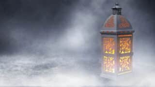 Decorative lantern with warm orange glow in a misty background.