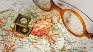 Vintage map of Asia with glasses and a magnifying loupe on top.