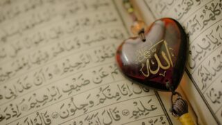 A page of the Qur'an and a heart-shaped decoration with “Allah” written in Arabic calligraphy.