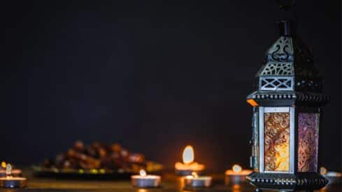 Ornate lantern with tea lights and dates against dark background, creating warm ambiance.