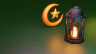 Glowing crescent moon, star, and lantern on green background, symbolizing Islam and celebrations.