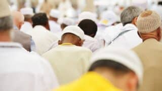 Group gathered wearing white caps, seen from behind, indicating a religious or cultural event.