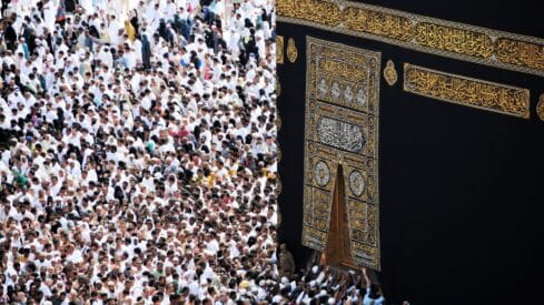 Crowd dressed in white near the Kaaba, adorned with gold calligraphy, Mecca's Masjid al-Haram.