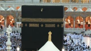 Kaaba draped in black with pilgrims in white at the Great Mosque of Mecca.