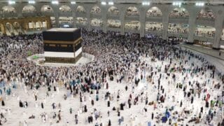 Kaaba surrounded by large crowd at Masjid al-Haram, Mecca, in a religious gathering.