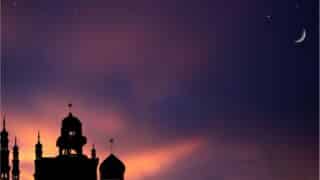 Silhouette of a mosque with minarets against a colorful sunset sky, crescent moon, and stars.