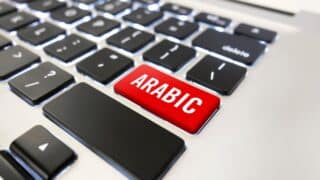 جزء من لوحة مفاتيح كمبيوتر وزر أحمر مكتوب عليه "ARABIC".