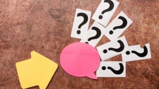 Yellow arrow points to pink speech bubble and question marks on textured brown background.