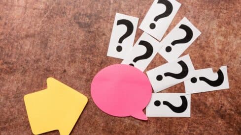 Yellow arrow points to pink speech bubble and question marks on textured brown background.