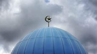 Blue dome with a crescent and star emblem beneath a cloudy sky.