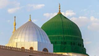 a silver one with golden spires, and a green prophet Mohamed dome against a blue sky.