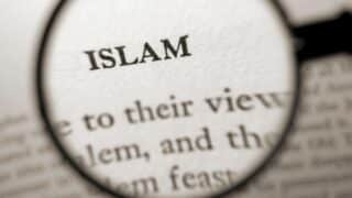 Magnifying glass highlights the word "Islam" in a blurred text.