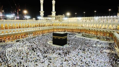 Aerial view of the Kaaba surrounded by people at night in Masjid al-Haram, Mecca.