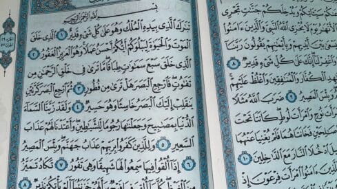 Two pages of quran with ornate blue borders from a religious manuscript.