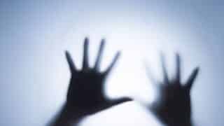 Silhouetted hands with fingers spread against bright, diffuse background creating shadow effect.