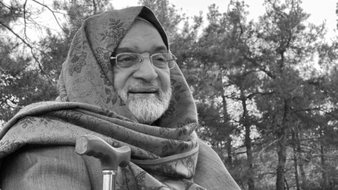 Smiling bearded man with glasses, showcasing wrinkles and a colorful scarf, capturing joy in portrait photography