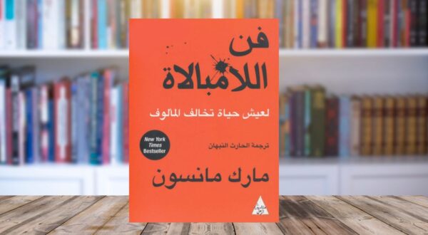 غلاف كتاب "فن اللامبالاة" برتقالي، على خلفية مكتبة، الأكثر مبيعًا.